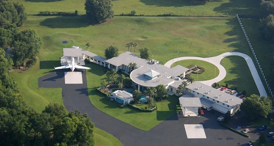 John Travolta house at Jumbolair Aviation Estates with private runway and aircraft parked outside luxury aviation mansion